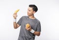 Young handsome asian sport man holding banana and hamburger with smiling isolated on white background. Royalty Free Stock Photo