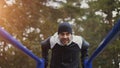 Young athlete man doing push-ups exercise on bars in winter park outdoors Royalty Free Stock Photo