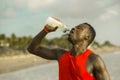 Young handsome and attractive black African American sport man tired and thirsty after running workout holding bottle drinking Royalty Free Stock Photo