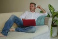 Young handsome and attractive happy man doing internet shopping thoughtful online with credit card sitting relaxed at home sofa co Royalty Free Stock Photo