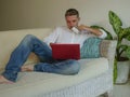 Young handsome and attractive happy man doing internet shopping thoughtful online with credit card sitting relaxed at home sofa co Royalty Free Stock Photo