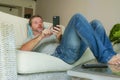 Young handsome attractive happy man using online dating app on mobile phone networking with smartphone lying at home couch Royalty Free Stock Photo