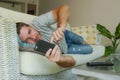 Young handsome attractive happy man using online dating app on mobile phone networking with smartphone lying at home couch Royalty Free Stock Photo