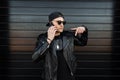 Young handsome attractive hipster man in a stylish leather jacket in a trendy black cap in dark fashionable sunglasses Royalty Free Stock Photo