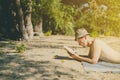 Young handsome attractive man in panama lying on sandy heaven beach and reading a book on a summer day Royalty Free Stock Photo