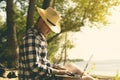 Young handsome attractive man sitting on the sandy tropical exotic beach on a summer resort working on a laptop Royalty Free Stock Photo