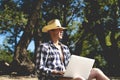 Young handsome attractive man sitting on the sandy tropical exotic beach on a summer resort working on a laptop Royalty Free Stock Photo