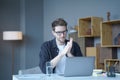 Young handsome austrian male freelancer wearing glasses looking at computer screen attentively Royalty Free Stock Photo