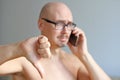 Young handsome bald man in black glasses talking on the phone. Closeup portrait of a man. Bad news, sadness. A man shows his thumb Royalty Free Stock Photo