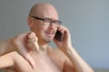 Young handsome bald man in black glasses talking on the phone. Closeup portrait of a man. Bad news, sadness. A man shows his thumb Royalty Free Stock Photo