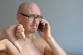 Young handsome bald man in black glasses talking on the phone. Closeup portrait of a man. Bad news, sadness. A man shows his thumb Royalty Free Stock Photo