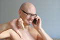 Young handsome bald man in black glasses talking on the phone. Closeup portrait of a man. Bad news, sadness. A man shows his thumb Royalty Free Stock Photo