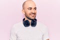 Young handsome bald man listening to music using headphones looking to side, relax profile pose with natural face and confident Royalty Free Stock Photo