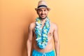 Young handsome bald man shirtless wearing swimwear and hawaiian lei with a happy and cool smile on face