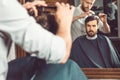 Young handsome barber making haircut of attractive man in barbershop