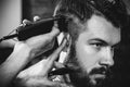 Young handsome barber making haircut for attractive man in barbershop