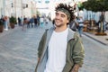 Young handsome beard man dressed stylish casual clothes, white t-shirt, green jacket, bandana posing outdoor. Smiling hipster with