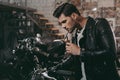 young handsome biker in black leather jacket with classic motorcycle