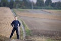 Young handsome blond child boy standing alone on ground road among golden grassy wheat fields on blurred foggy green trees and me