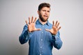 Young handsome blond man with beard and blue eyes wearing casual denim shirt afraid and terrified with fear expression stop Royalty Free Stock Photo