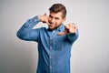 Young handsome blond man with beard and blue eyes wearing casual denim shirt smiling doing talking on the telephone gesture and Royalty Free Stock Photo