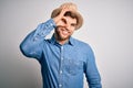 Young handsome blond man with beard and blue eyes wearing denim shirt and summer hat doing ok gesture with hand smiling, eye Royalty Free Stock Photo