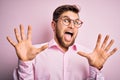 Young handsome blond man with beard and blue eyes wearing pink shirt and glasses afraid and terrified with fear expression stop Royalty Free Stock Photo
