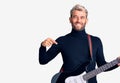 Young handsome blond man playing electric guitar pointing finger to one self smiling happy and proud Royalty Free Stock Photo