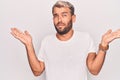 Young handsome blond man wearing casual t-shirt standing over isolated white background clueless and confused with open arms, no Royalty Free Stock Photo