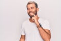 Young handsome blond man wearing casual t-shirt standing over isolated white background smiling looking confident at the camera Royalty Free Stock Photo