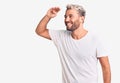 Young handsome blond man wearing casual t-shirt very happy and smiling looking far away with hand over head Royalty Free Stock Photo