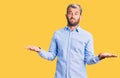 Young handsome blond man wearing elegant shirt clueless and confused with open arms, no idea concept Royalty Free Stock Photo