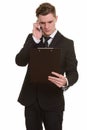 Young handsome blonde businessman in suit holding clipboard and using phone Royalty Free Stock Photo