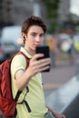 Young handsome boy with headphones takes selfie with smartphone, summer park outdoor. 15 years old teenager using mobile phone, Royalty Free Stock Photo