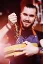 Brewer man pours beer malt with a wooden plate on the background of a brewery