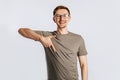 Young handsome brunet man with beard wearing glasses showing thumb down and smiling on white isolated background Royalty Free Stock Photo