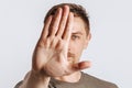 Young handsome brunette man with beard stretched out his hand forward and says STOP on white isolated background Royalty Free Stock Photo