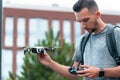 Young Handsome Brunette Man Launching Drone Quadcopter and Looking At Remote Controller Joystick. Urban Stlilysh