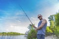 Young handsome brutal caucasian man in casual outfit fishing on Royalty Free Stock Photo