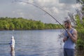 Young handsome brutal caucasian man in casual outfit fishing on Royalty Free Stock Photo