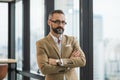 Young handsome business bearded man standing near window with arms crossed in office work place Royalty Free Stock Photo