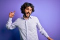 Young handsome business man with beard wearing shirt standing over purple background Dancing happy and cheerful, smiling moving Royalty Free Stock Photo