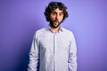 Young handsome business man with beard wearing shirt standing over purple background In shock face, looking skeptical and Royalty Free Stock Photo