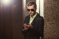 Young handsome business man in black blazer using smart phone