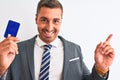 Young handsome business man holding credit card over isolated background very happy pointing with hand and finger to the side Royalty Free Stock Photo