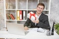 Young handsome business man preparing present for colleague at his working place in office looking happy. Study education, work Royalty Free Stock Photo