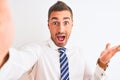 Young handsome business man taking selfie using smartphone over isolated background very happy and excited, winner expression Royalty Free Stock Photo