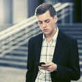 Young handsome business man using smart phone walking in city street Royalty Free Stock Photo