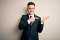 Young handsome business man wearing elegant suit and tie over isolated background amazed and smiling to the camera while Royalty Free Stock Photo