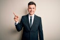 Young handsome business man wearing elegant suit and tie over isolated background with a big smile on face, pointing with hand Royalty Free Stock Photo